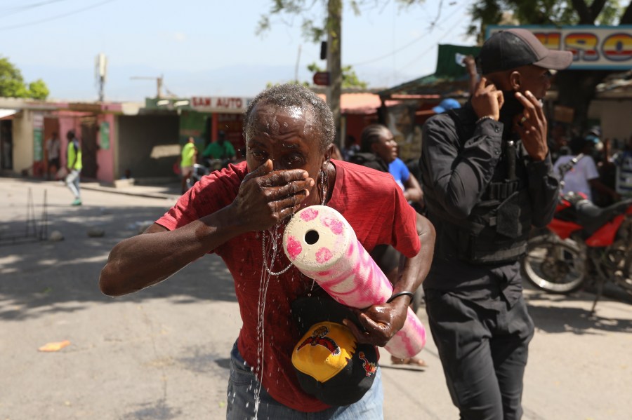 A demonstrator is affected by tear gas fired by police to disperse protesters demanding that police and the Prime Minister take immediate action against gangs in Port-au-Prince, Haiti, Monday, Aug. 19, 2024. (AP Photo/Odelyn Joseph)