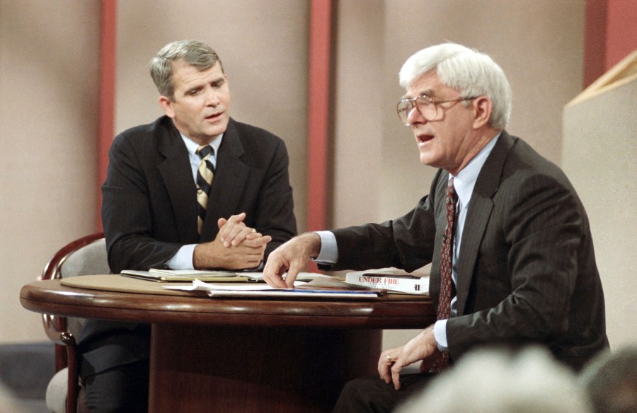 FILE - Iran-contra figure Oliver North appears with host Phil Donahue in New York to promote his new book "Under Fire: An American Story" on Oct. 24, 1991. Donahue, whose pioneering daytime talk show launched an indelible television genre, has died. He was 88. (AP Photo/Richard Drew, File)