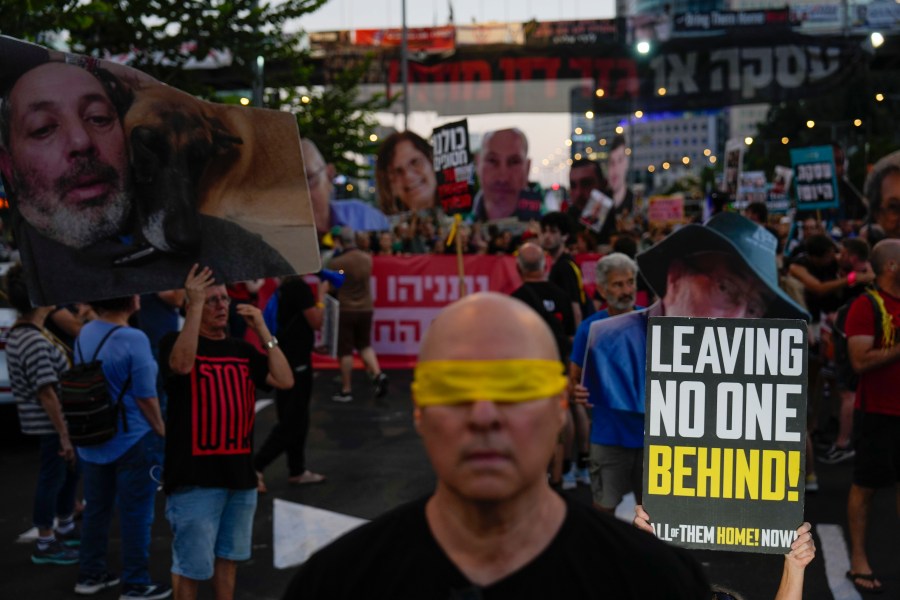 Protesters stand with large cutout photos of slain hostages and other hostages with relatives of hostages taken by Hamas militants to the Gaza Strip, to honor the memories of six men whose bodies were returned and to call for a deal to release the remaining captives, in Tel Aviv, Israel, Tuesday, Aug. 20, 2024. (AP Photo/Ariel Schalit)