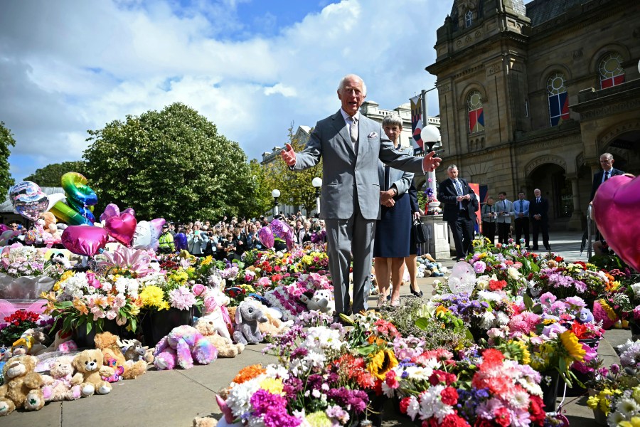 Britain's King Charles III looks at the tributes outside Southport Town Hall, in Southport, England, Tuesday Aug. 20, 2024, as he meets members of the local community, following the July 29 attack at a children's dance party. (Paul Ellis/Pool via AP)