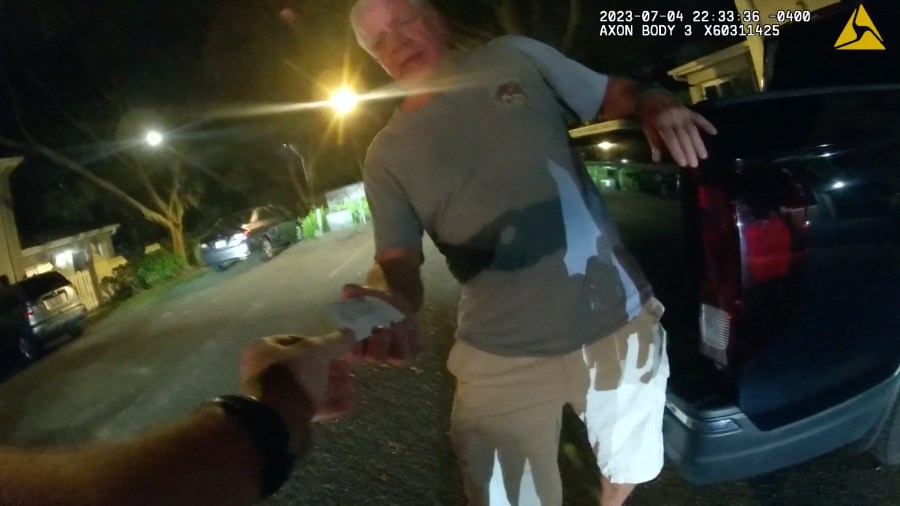 FILE - In this image from video provided by the Tampa Police Department, Joseph Ruddy, a prosecutor with the U.S. Attorney's Office in Tampa, hands his business card to Officer Taylor Grant, outside his home in Temple Terrace, Fla., on the evening of July 4, 2023. (Officer Taylor Grant/Tampa Police Department, File)