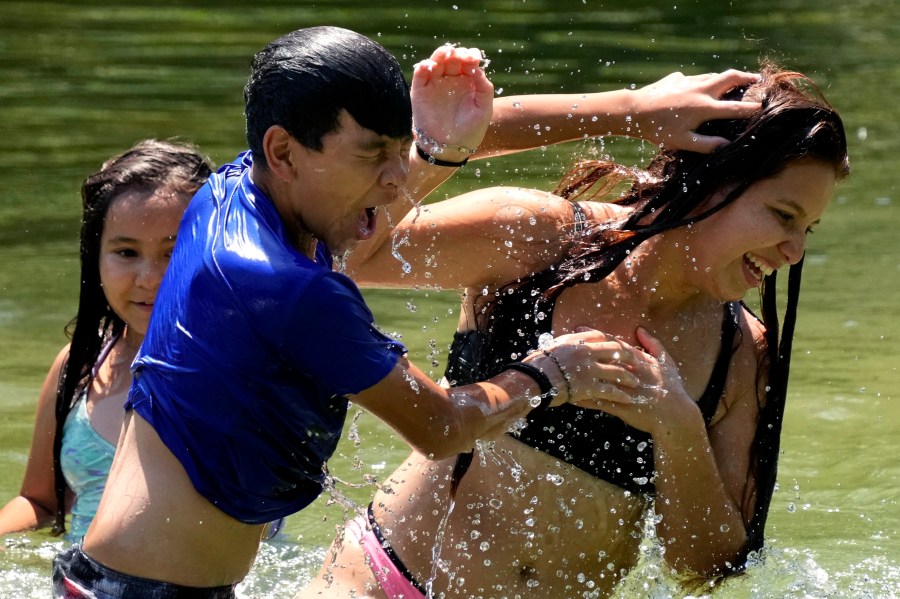 Romeo Gutierrez, center, plays with siblings Cipporah, left, and Leeann, right, as they keep cool in the Guadalupe River, Wednesday, Aug. 21, 2024, in New Braunfels, Texas. (AP Photo/Eric Gay)