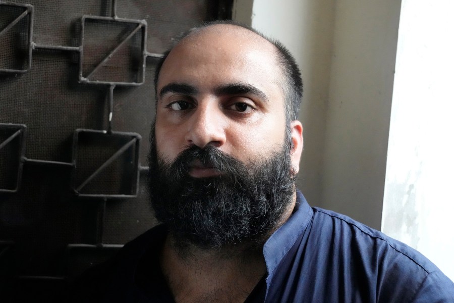 Farhan Asif, center, a freelance web developer who was arrested and charged with cyber terrorism for his alleged role in spreading misinformation that led to widespread rioting in the U.K. earlier this month, waits for his court appearance, in Lahore, Pakistan, Thursday, Aug. 22, 2024. (AP Photo/K.M. Chaudary)