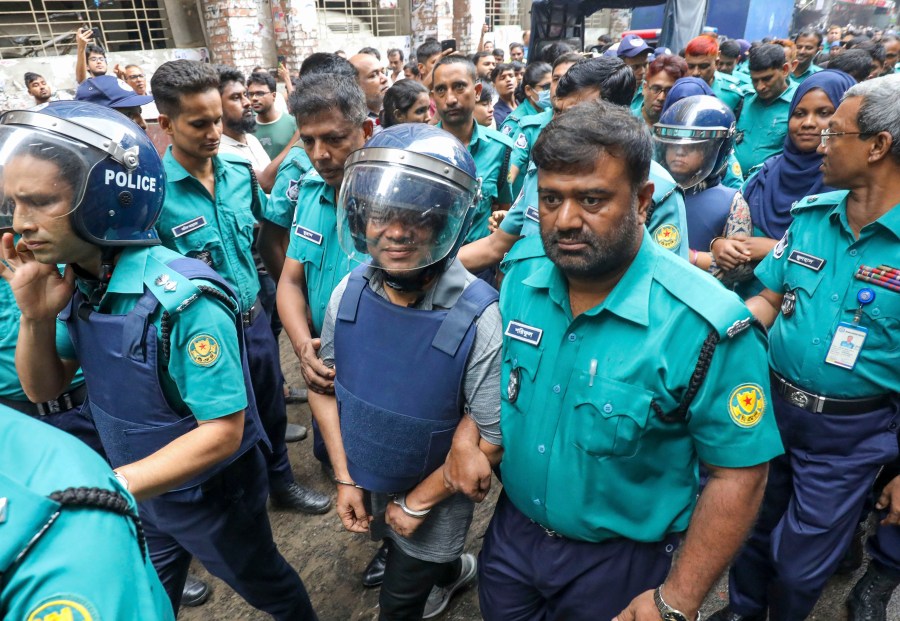 Police officers escort Shakil Ahmed, Ekattor television's former head of news, center, and its former chief correspondent Farzana Rupa, rear right in helmet, to the court of the Chief Metropolitan Magistrate in Dhaka, Bangladesh, Thursday, Aug. 22, 2024. (AP Photo)