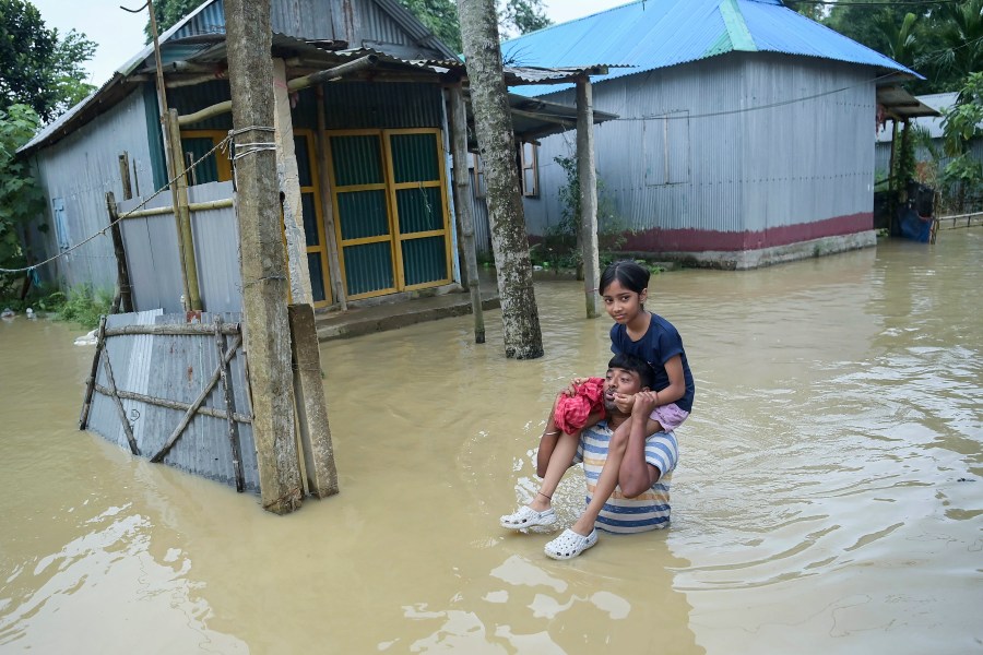 A young girl is carried on the shoulder by a man as they navigate flood waters following incessant rains in Agartala, north eastern Tripura state, India, Tuesday, Aug. 20, 2024. (AP Photo/Abhisek Saha)