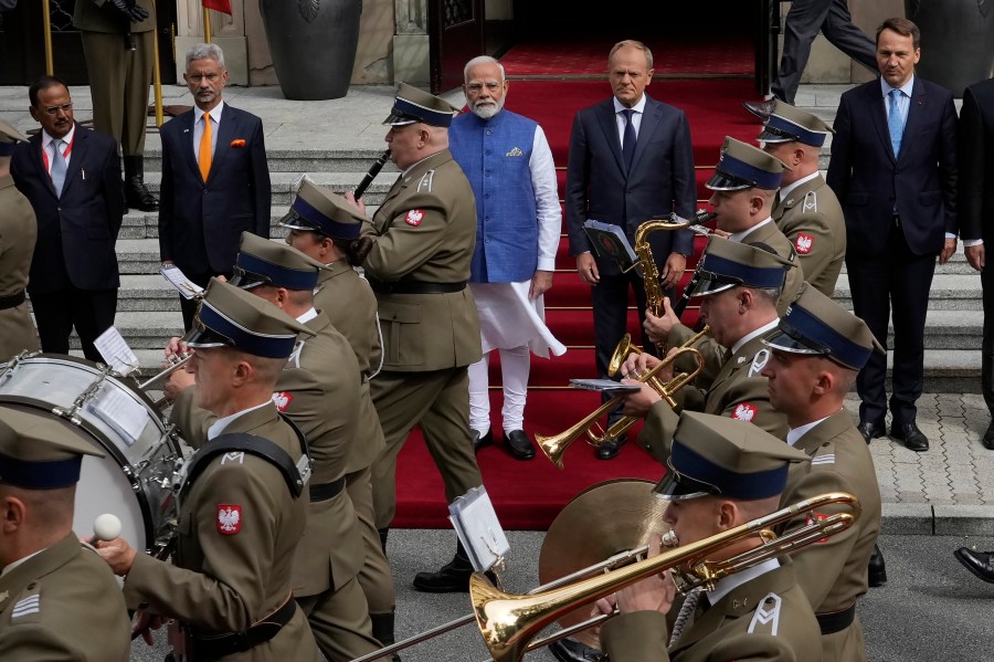 Indian Prime Minister Narendra Modi, center left in blue, stands with his Polish counterpart Donald Tusk, center right, to inspect an honor guard before talks in Warsaw, Poland, Thursday, Aug. 22, 2024. (AP Photo/Czarek Sokolowski)