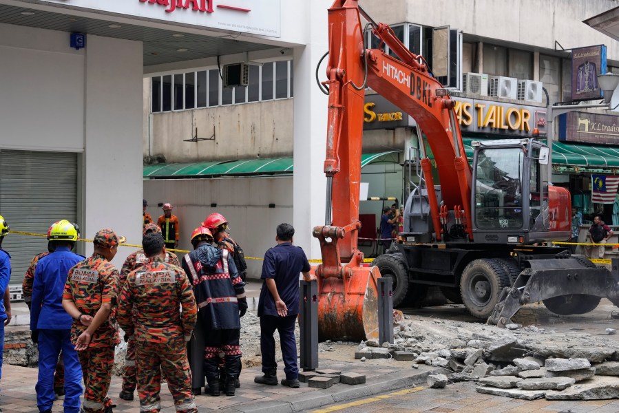 Fire and Rescue department use crane to dig a deep sinkhole after receiving reports that a woman has fallen into the sinkhole after a section of the sidewalk caved in Kuala Lumpur, Friday, Aug. 23, 2024. (AP Photo/Vincent Thian)