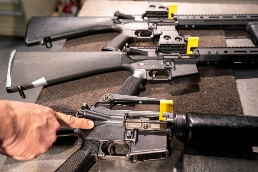 FILE - A finger points to a pin of an M-16 that makes it a fully automatic machine gun receiver, in a row of AR-15 style rifles at the Bureau of Alcohol, Tobacco, Firearms, and Explosives (ATF) National Services Center, March 2, 2023, in Martinsburg, W.Va. (AP Photo/Alex Brandon, File)