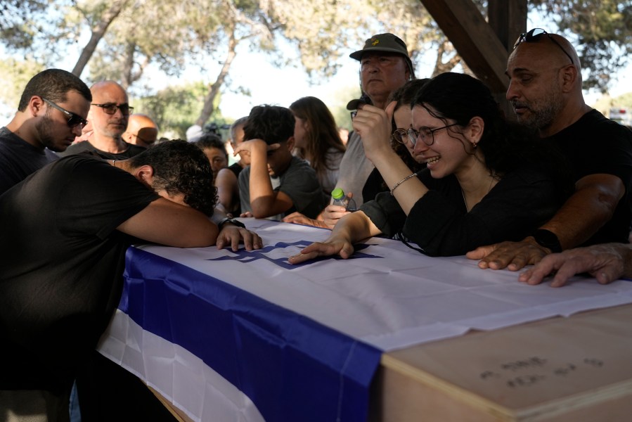 Family members mourn over the coffin of Yoram Metzger during his funeral at a cemetery of the kibbutz Nir Oz, southern Israel, Thursday, Aug. 22, 2024. Metzger's body was one the six bodies of hostages, taken in Hamas' Oct. 7 attack, recovered by Israel's military during an operation in the Gaza Strip. (AP Photo/Tsafrir Abayov)