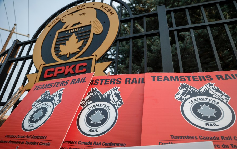 Teamsters Canada Rail Conference picket sign lean up againts a CPKC logo outside the company's headquarters in Calgary, Alta., Friday, Aug. 23, 2024.(Jeff McIntosh /The Canadian Press via AP)