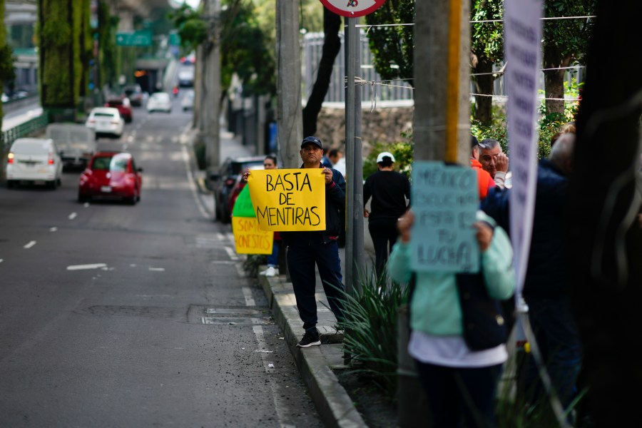 A unionized federal court worker holds a sign that reads in Spanish, "Enough of the lies" as they strike over reforms that would make all judges stand for election, outside a federal court in Mexico City, Wednesday, Aug. 21, 2024. (AP Photo/Eduardo Verdugo)