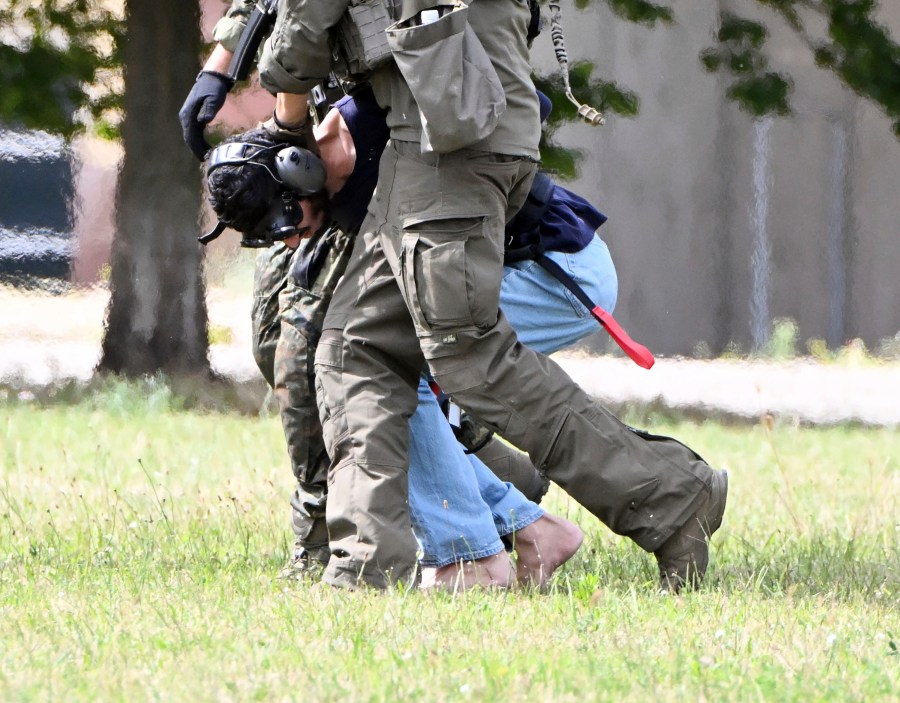 The alleged perpetrator of the knife attack in Solingen is escorted from a helicopter in Karlsruhe, Germany, Sunday, Aug. 25, 2024. German police say a 26-year-old man has turned himself in, saying he was responsible for the deadly Solingen knife attack that left three dead and eight wounded at a festival marking the city’s 650th anniversary. (Uli Deck/dpa via AP)