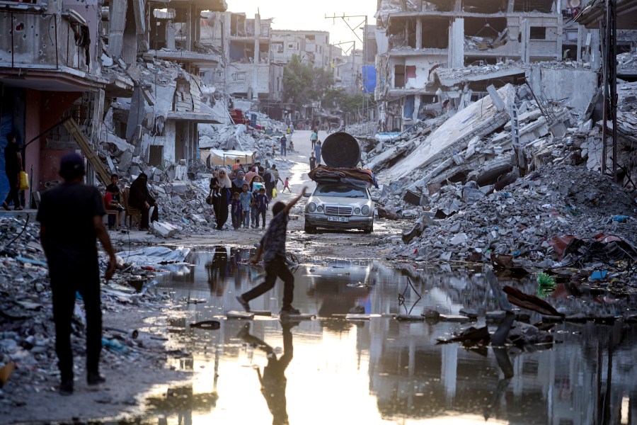 FILE - Palestinians displaced by the Israeli air and ground offensive on the Gaza Strip, walk past sewage flowing into the streets of the southern town of Khan Younis, Gaza Strip, on July 4, 2024. Israel’s military on Sunday Aug. 25, 2024 said polio vaccines for more than 1 million people had been delivered to Gaza, after the first confirmed case of the disease in the territory in a quarter-century. (AP Photo/Jehad Alshrafi, File)