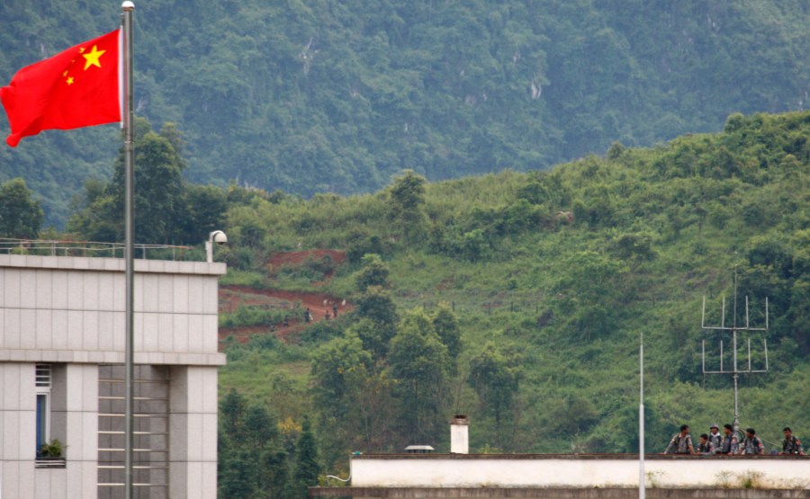 FILE - Myanmar government troops stand on a rooftop on the Myanmar side, near a Chinese flag from the Chinese border town of Nansan in southwestern China's Yunnan province, Sunday, Aug 30, 2009. (AP Photo/Ng Han Guan. File)