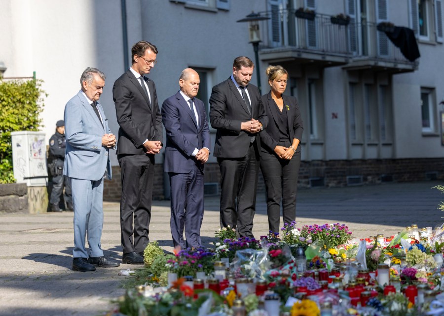 From left, Herbert Reul, Minister of the Interior of North Rhine-Westphalia, Hendrik Wüst, Minister President of North Rhine-Westphalia, German Chancellor Olaf Scholz, Tim Kurzbach, Mayor of Solingen, and Mona Neubaur, Deputy Minister President of North Rhine-Westphalia, pay their respects, in front of floral tributes left, near the scene of a knife attack, in Solingen, Germany, Monday, Aug. 26, 2024. (Thomas Banneyer/dpa via AP)