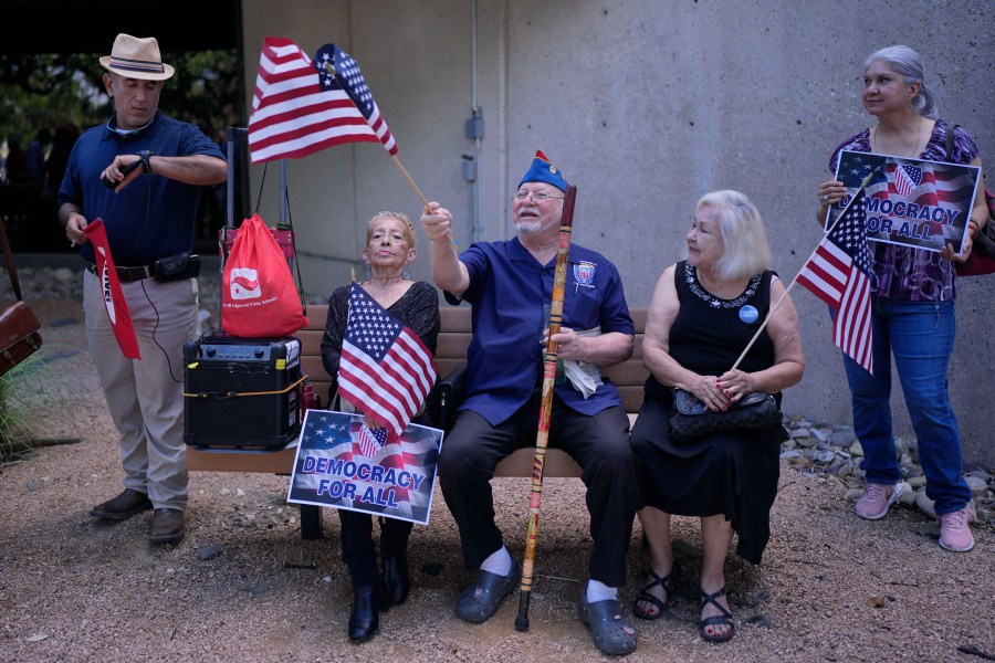 Roman Rena, center, waves a flag at a news conference where Officials with the League of United Latin American Citizens, or LULAC, held a news conference to respond to allegations by Texas Attorney General Ken Paxton, Monday, Aug. 26, 2024, in San Antonio. (AP Photo/Eric Gay)