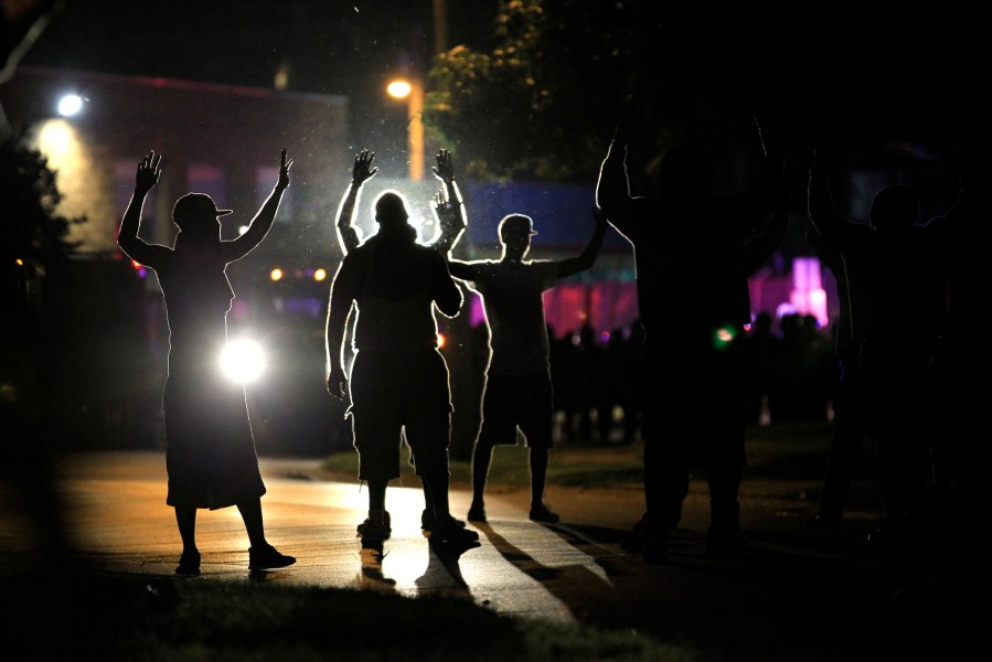 FILE - People raise their hands as police, trying to get them to disperse, move toward them during protests on Aug. 11, 2014 over the police shooting of Michael Brown in Ferguson, Mo. (AP Photo/Jeff Roberson, File)