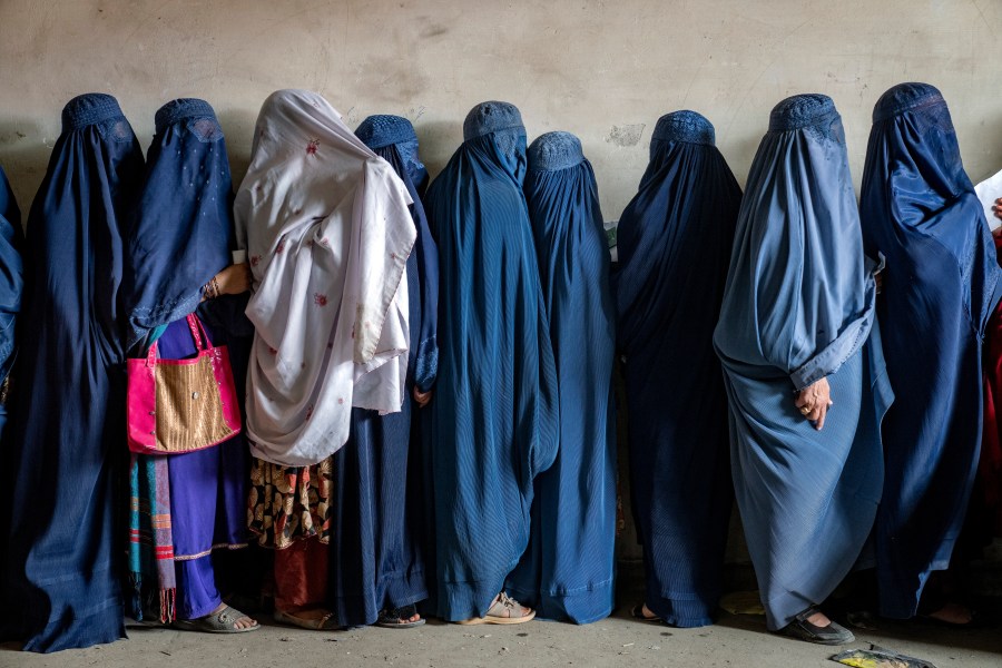 FILE - Afghan women wait to receive food rations distributed by a humanitarian aid group, in Kabul, Afghanistan, May 23, 2023. The Taliban Virtue and Vice Ministry had on May 7, 2022 ,said women in public must wear all-encompassing robes and cover their faces except for their eyes. (AP Photo/Ebrahim Noroozi, File)