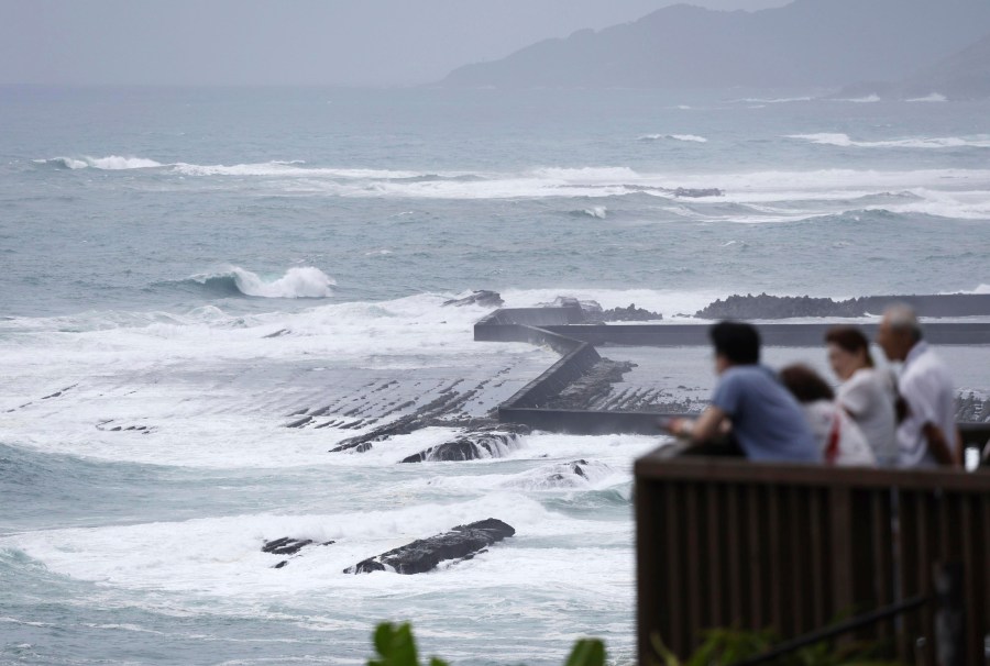 People watch waves hit a coastal area in Miyazaki, western Japan, Tuesday, Aug. 27, 2024, as a typhoon is approaching. (Hidetaka Komukai/Kyodo News via AP)