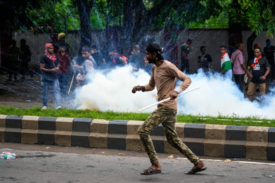 Protestors against the rape and murder of a resident doctor at a government hospital earlier this month, runs as police fire tear gas, in Kolkata, India, Tuesday, Aug. 27, 2024. (AP Photo/Bikas Das)