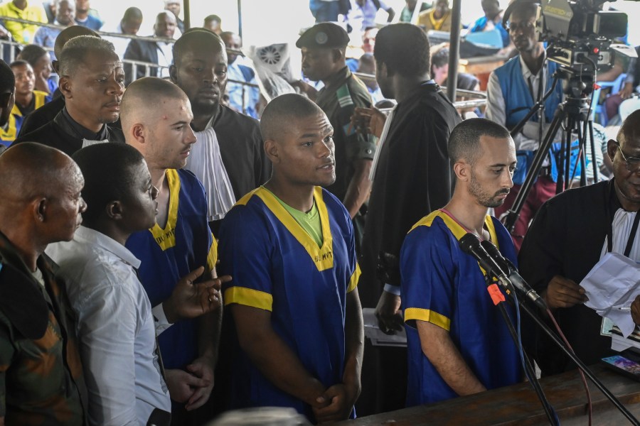 FILE - From left, Tyler Thompson Jr., Marcel Malanga and Benjamin Reuben Zalman-Polun, all American citizens, face the court in Kinshasa, Congo, with 52 other defendants, June 7, 2024, accused of a role in the attempted coup in Congo led by little-known opposition figure Christian Malanga in which six people were killed. (AP Photo/Samy Ntumba Shambuyi, File)