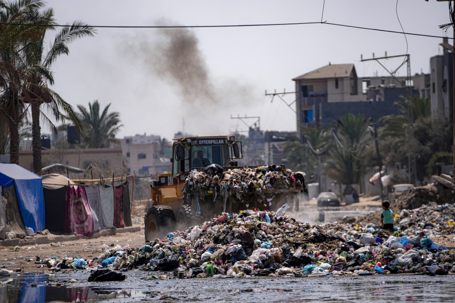 A bulldozer cleans up plastic and other waste materials at a street in Deir al-Balah, central Gaza Strip, Tuesday, Aug. 27, 2024. (AP Photo/Abdel Kareem Hana)