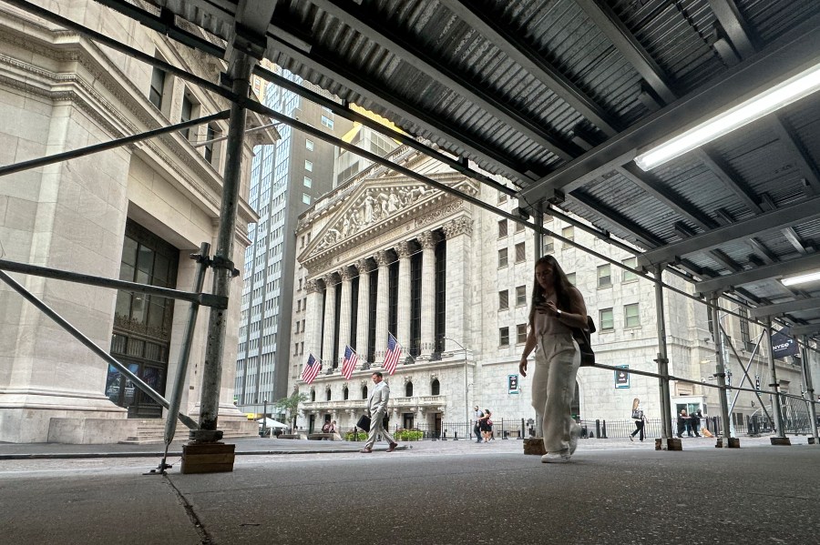 People pass the New York Stock Exchange, at rear, on Tuesday, Aug. 27, 2024, in New York. (AP Photo/Peter Morgan)