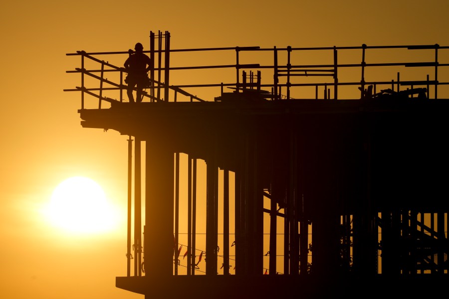 Construction workers start their day as the sun rises on the new Republic Airlines headquarters building in Carmel, Ind., Tuesday, Aug. 27, 2024. (AP Photo/Michael Conroy)