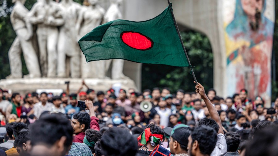 A student waves Bangladesh's national flag, during a protest to demand accountability and trial against the country's ousted Prime Minister Sheikh Hasina, near Dhaka University in the capital on August 12, 2024. Bangladesh was experiencing a "student-led revolution" after the ouster of premier Sheikh Hasina, the South Asian country's new interim leader Muhammad Yunus said. (Photo by Luis TATO / AFP) (Photo by LUIS TATO/AFP via Getty Images)