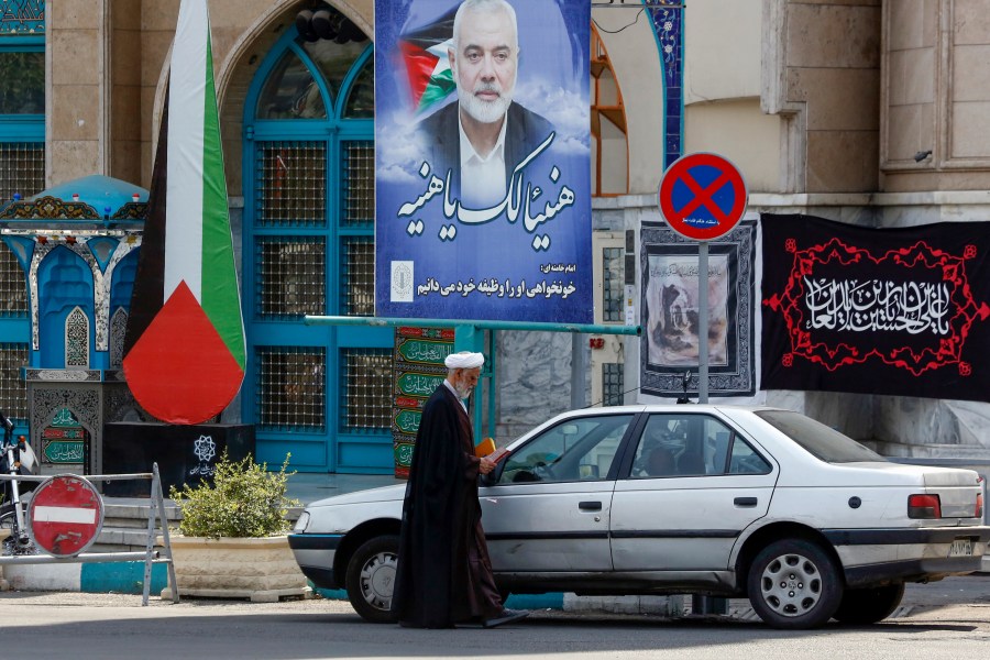 A cleric stands next to a poster depicting slain leader of the Palestinian Hamas group Ismail Haniyeh at Tehran's Palestine square on August 8, 2024, amid regional tensions during the ongoing war between Israel and Hamas in the Gaza Strip. (Photo by AFP) (Photo by -/AFP via Getty Images)