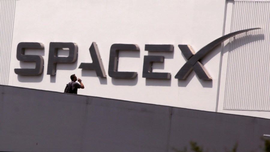 An employee walks across the bridge from parking to SpaceX in Hawthorne on July 17, 2024. Elon Musk said Tuesday on X that he is moving the headquarters of both SpaceX and the social media platform formerly known as Twitter to Texas citing several criticisms he has of California. (Genaro Molina/Los Angeles Times via Getty Images)