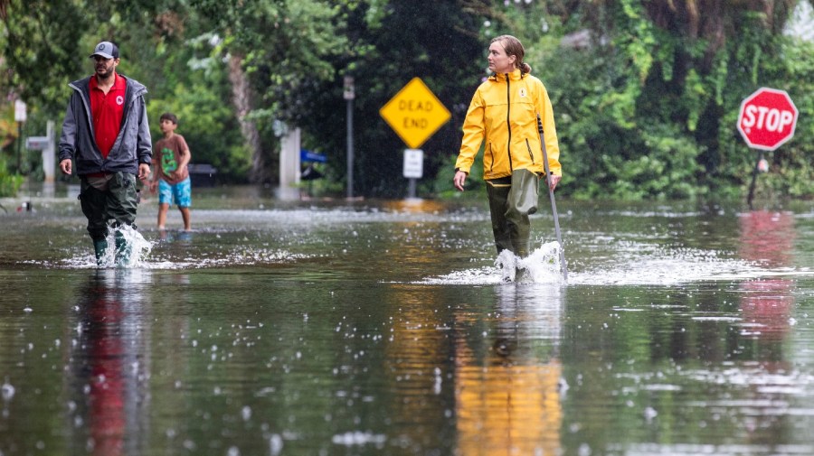 Rebecca Fanning, right, who works for the town of Sullivan's Island, inspects flood waters as Charles Drayton, also an employee of Sullivan's Island and his son McKain, 8, walk behind on Atlantic Ave. as Tropical Storm Debby approaches, Wednesday, Aug. 7, 2024, in Sullivan's Island, S.C. (AP Photo/Mic Smith)