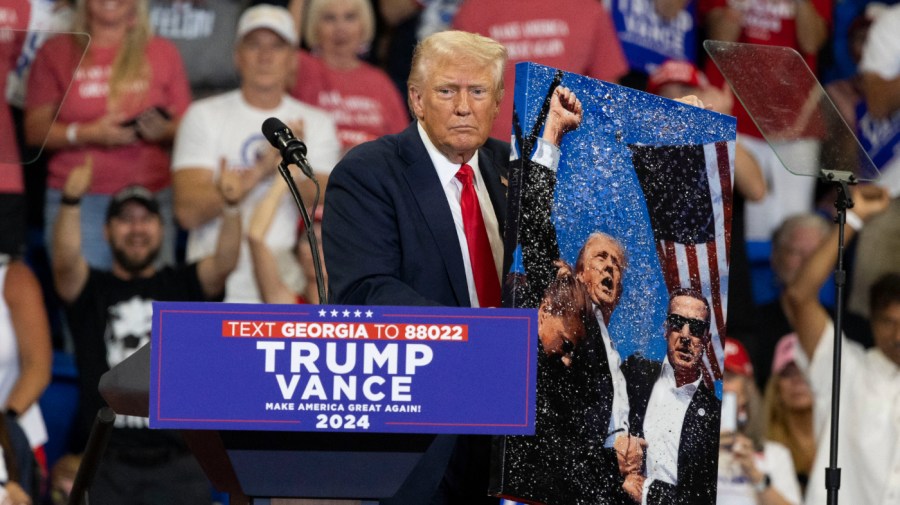 Former US President and 2024 Republican presidential candidate Donald Trump holds up a painting of himself during a campaign rally at the Georgia State University Convocation Center in Atlanta, Georgia, on August 3, 2024. (Photo by CHRISTIAN MONTERROSA / AFP) (Photo by CHRISTIAN MONTERROSA/AFP via Getty Images)