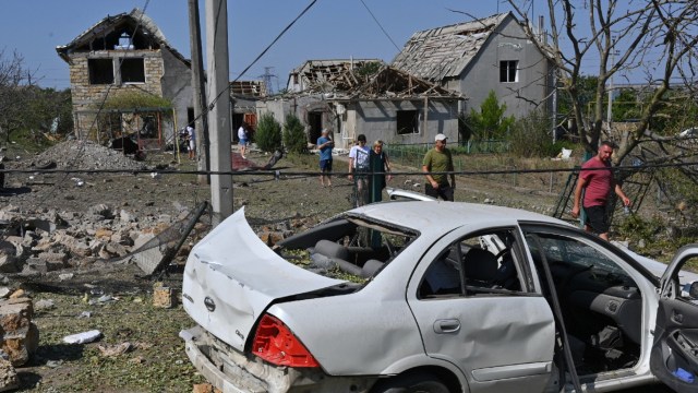 People walk in front of their damaged houses after Russian rocket attack in Usatove village near Odesa, Ukraine, Monday, Aug. 26, 2024.