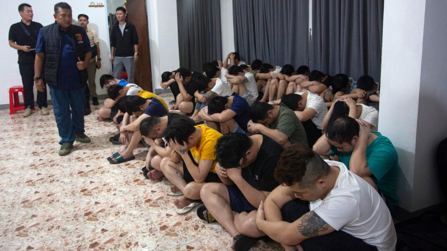 Title: Indonesia China Romance Scams Image ID: 23242473193610 Article: Plain-clothed police officers detain Chinese nationals following a raid on a shophouse in Batam, Indonesia, Tuesday, Aug. 29, 2023. Indonesian police said Wednesday they have arrested a number of Chinese citizens for involvement in a cross-border telephone and online romance scam syndicate after receiving a tip from the Chinese security ministry. (AP Photo/Andaru)